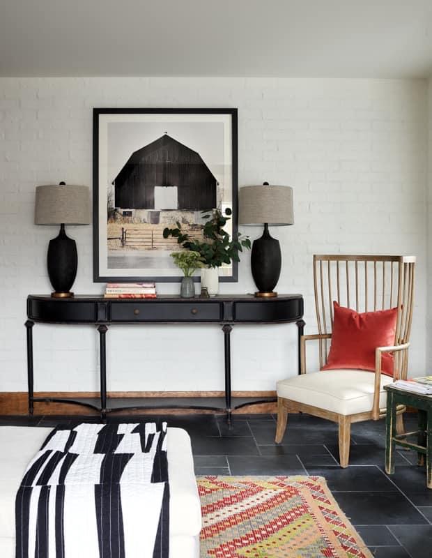 Black and white quilted throw draped over an ottoman in a styled living room